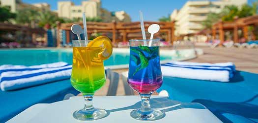 Two cocktail drinks by a tropical pool Two cocktail drinks on the side of a swimming pool in tropical summer holiday resort