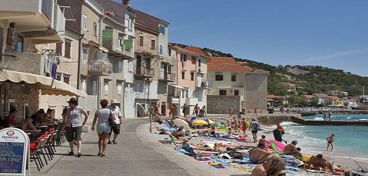 Baska street, Croatia BASKA, CROATIA - People walk, sunbathe and swim on the seafront and beach of mediterranean town of island Krk on Baska, Croatia. Baska Voda is a municipality in the Split-Dalmatia County.
