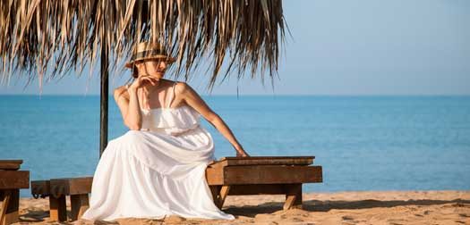 Beautiful young woman resting on the sandy beach Beautiful young woman sitting on the bench on the sandy beach
