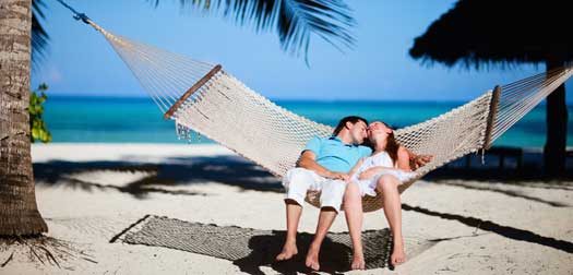 Young romantic couple relaxing in hammock on tropical beach