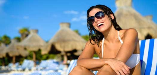 Happy woman on vacation at tropical resort beach Joyful woman at tropical resort caribbean beach. Summertime vacation tourism and travel concept. Beautiful brunette sunbathing and relaxing at Mayan Riviera, Mexico.