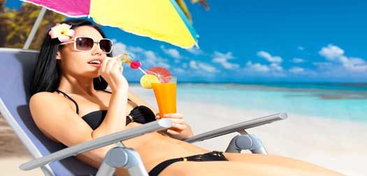Happy woman on holiday enjoying at beach Happy brunette woman on holiday drinking orange juice on the beach