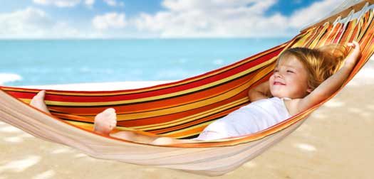 Child relaxing in a hammock on the sea beach