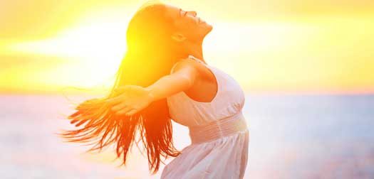 Enjoyment - free happy woman enjoying sunset Enjoyment - free happy woman enjoying sunset. Beautiful woman in a white dress embracing the golden sunshine glow of sunset with her arms outspread and face raised to the sky enjoying peace and serenity of nature