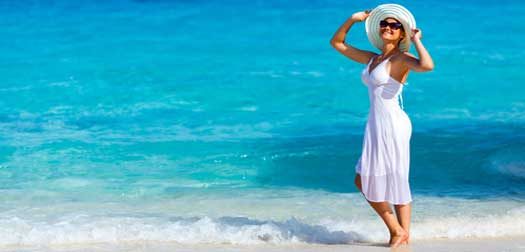 Young woman in a white dress walking on the beach Young woman in a white dress walking on the tropical beautiful beach