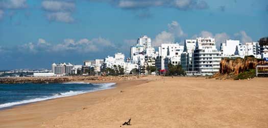 beach and sea in the portugal part allgarve with the village quarteira as background
